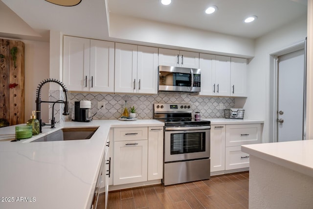 kitchen with tasteful backsplash, white cabinetry, appliances with stainless steel finishes, and sink