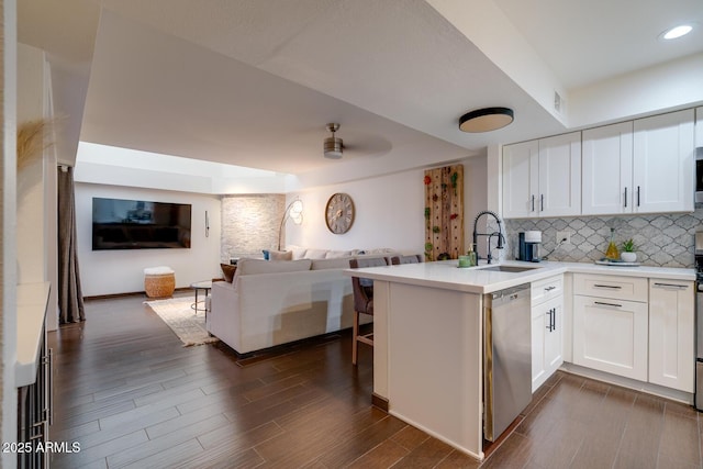 kitchen featuring a tray ceiling, kitchen peninsula, dishwasher, and white cabinets