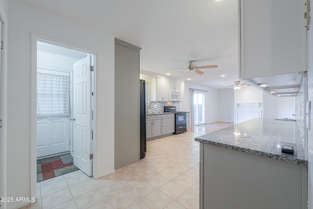 kitchen featuring light tile patterned floors, freestanding refrigerator, electric stove, a ceiling fan, and white microwave
