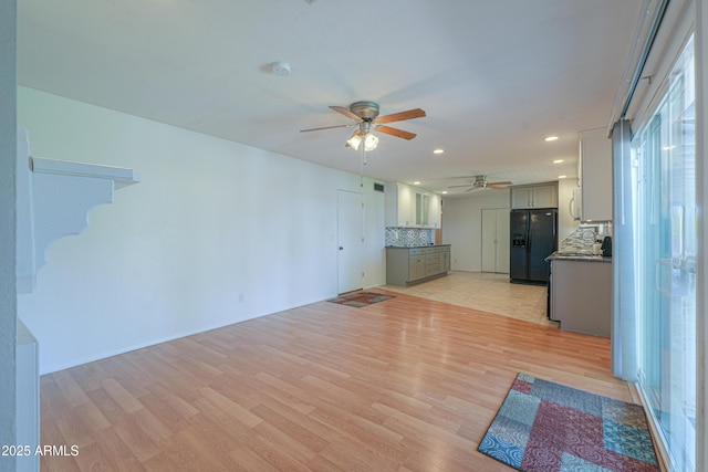 unfurnished living room with light wood finished floors, a ceiling fan, recessed lighting, and stairs