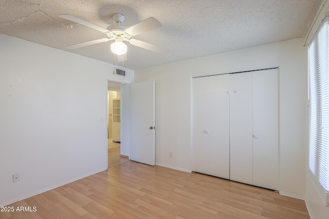 unfurnished bedroom with light wood finished floors, a textured ceiling, and a closet