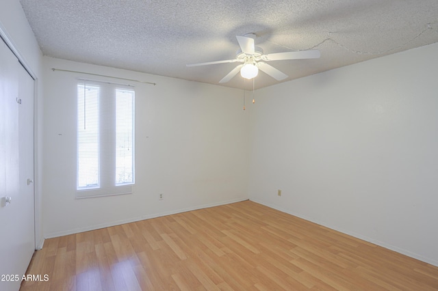 unfurnished room featuring baseboards, ceiling fan, light wood-style floors, and a textured ceiling