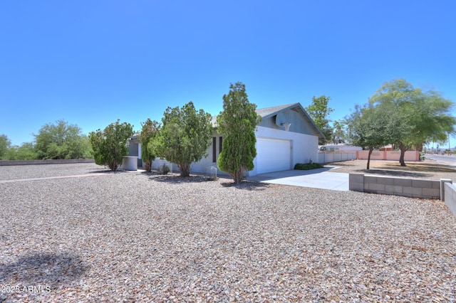 view of front facade featuring fence, stucco siding, driveway, and an attached garage