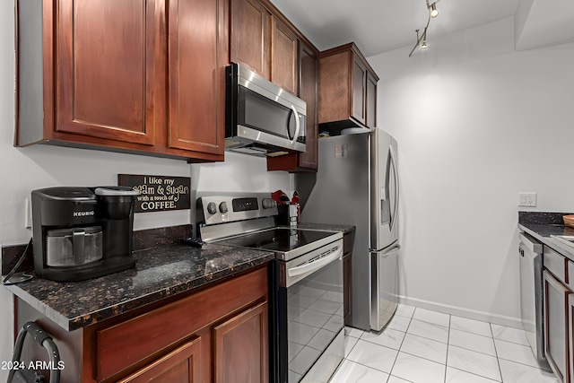 kitchen with dark stone countertops, light tile patterned floors, and stainless steel appliances