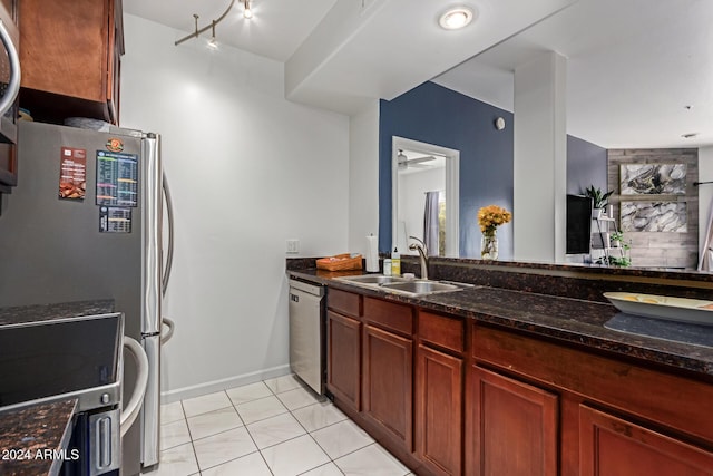 kitchen with dark stone counters, sink, ceiling fan, light tile patterned floors, and stainless steel appliances