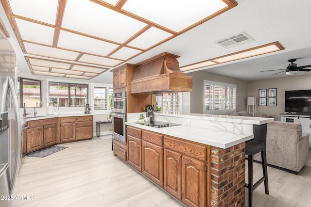 kitchen with visible vents, custom exhaust hood, a peninsula, appliances with stainless steel finishes, and open floor plan