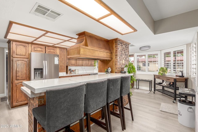 kitchen with light wood-style floors, light countertops, stainless steel fridge with ice dispenser, and visible vents