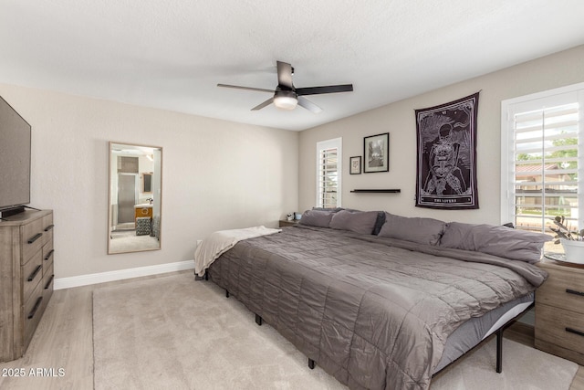 bedroom featuring ceiling fan, baseboards, a textured ceiling, and light wood-style flooring