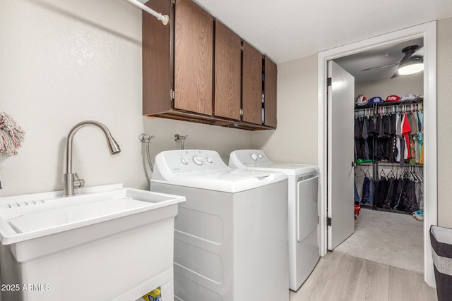 laundry room featuring light wood-type flooring, washer and dryer, a sink, cabinet space, and ceiling fan