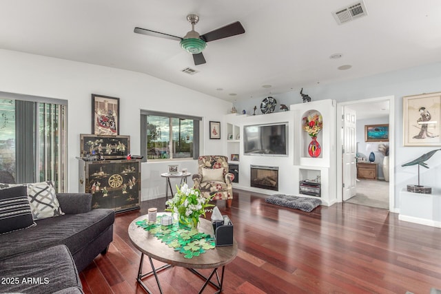 living room with visible vents, wood finished floors, lofted ceiling, and a glass covered fireplace