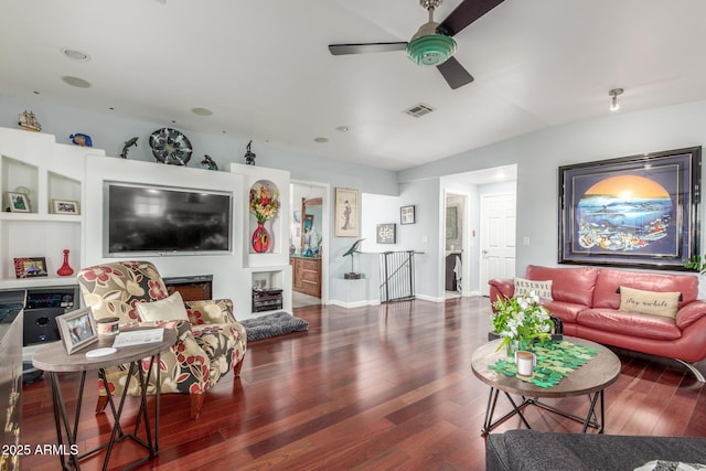 living area featuring a ceiling fan, wood finished floors, visible vents, baseboards, and lofted ceiling