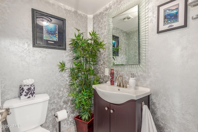 bathroom featuring vanity, toilet, and visible vents