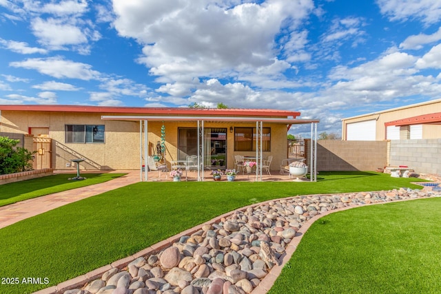 rear view of property with a patio area, a yard, fence, and stucco siding