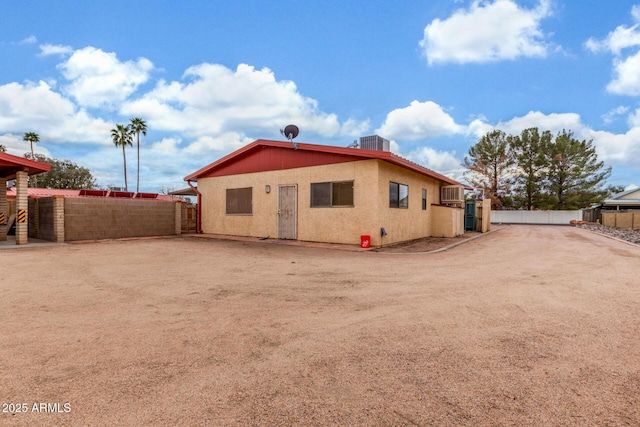 rear view of house featuring central air condition unit, stucco siding, and fence