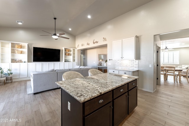 kitchen featuring light stone countertops, dark brown cabinetry, white cabinets, and light wood-type flooring