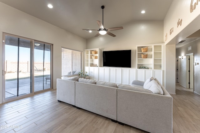 living room with ceiling fan, light wood-type flooring, and high vaulted ceiling