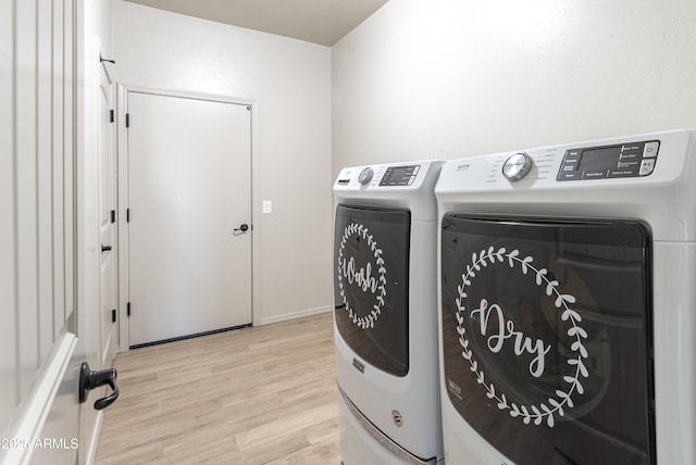 clothes washing area featuring washing machine and dryer and light hardwood / wood-style flooring