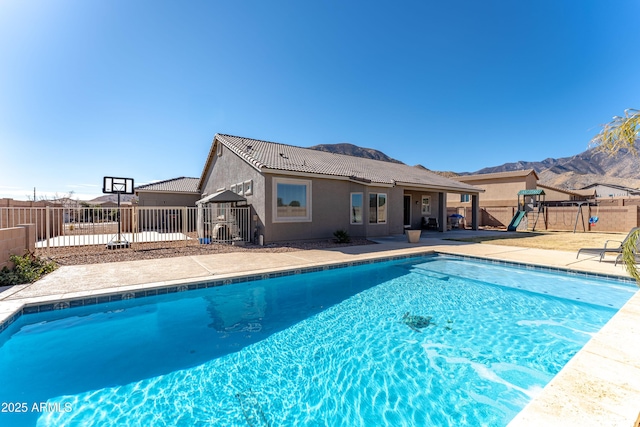 view of pool with a playground and a mountain view