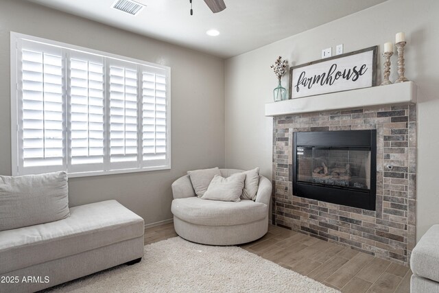 living room with hardwood / wood-style flooring, ceiling fan, and a fireplace