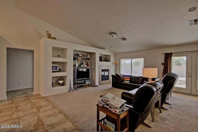 living room with built in shelves, a tiled fireplace, plenty of natural light, and vaulted ceiling