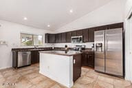 kitchen with a kitchen island, dark brown cabinetry, lofted ceiling, and stainless steel appliances