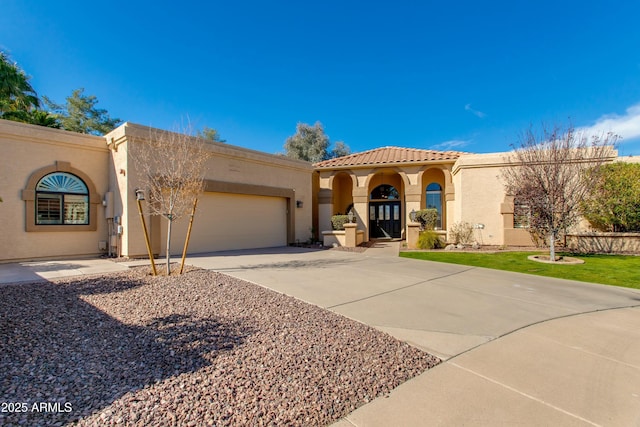 mediterranean / spanish-style house featuring a garage, concrete driveway, a tiled roof, and stucco siding