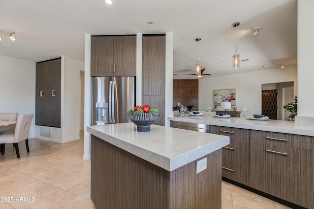 kitchen featuring light tile patterned floors, stainless steel fridge with ice dispenser, modern cabinets, a kitchen island, and light countertops