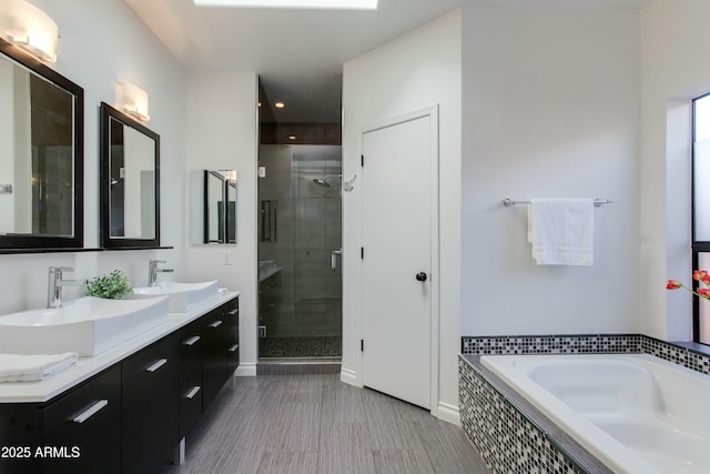 full bathroom with double vanity, a garden tub, a shower stall, and a sink