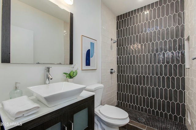 full bathroom with tiled shower, vanity, and toilet