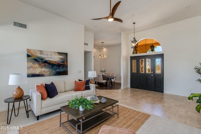 living room with baseboards, ceiling fan with notable chandelier, visible vents, and light tile patterned flooring