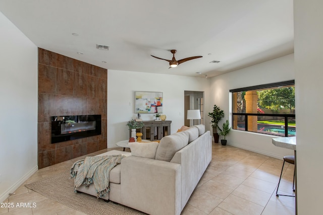 living area featuring a tile fireplace, visible vents, baseboards, and light tile patterned floors