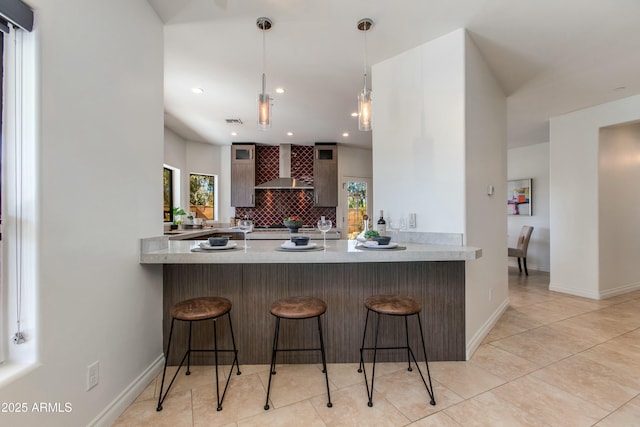 kitchen featuring glass insert cabinets, a kitchen breakfast bar, light countertops, and wall chimney exhaust hood