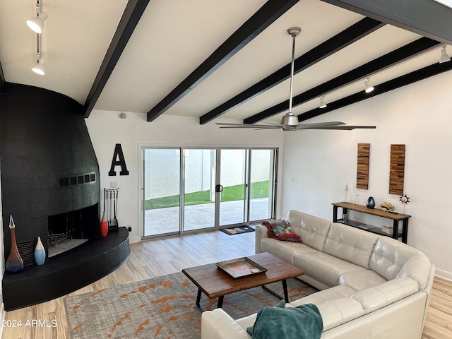 living room featuring ceiling fan, vaulted ceiling with beams, a fireplace, and light hardwood / wood-style flooring