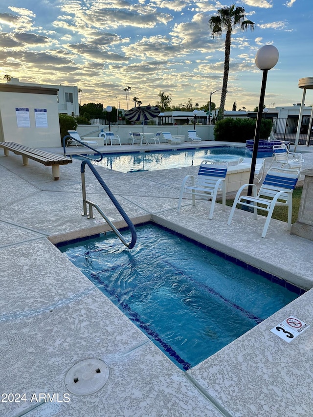 pool at dusk featuring a patio