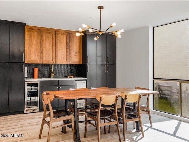 kitchen with sink, decorative light fixtures, beverage cooler, light hardwood / wood-style floors, and decorative backsplash