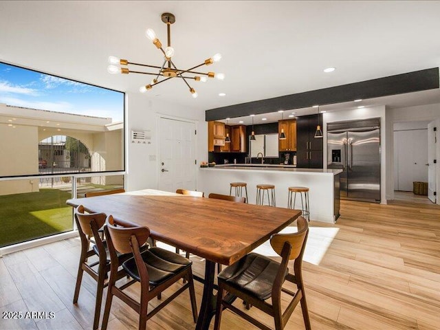 dining space with sink, a notable chandelier, and light hardwood / wood-style flooring