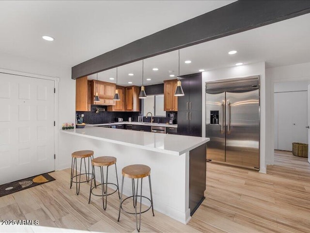 kitchen with hanging light fixtures, stainless steel built in fridge, backsplash, and beamed ceiling