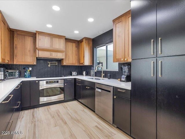 kitchen with premium range hood, appliances with stainless steel finishes, sink, backsplash, and light wood-type flooring