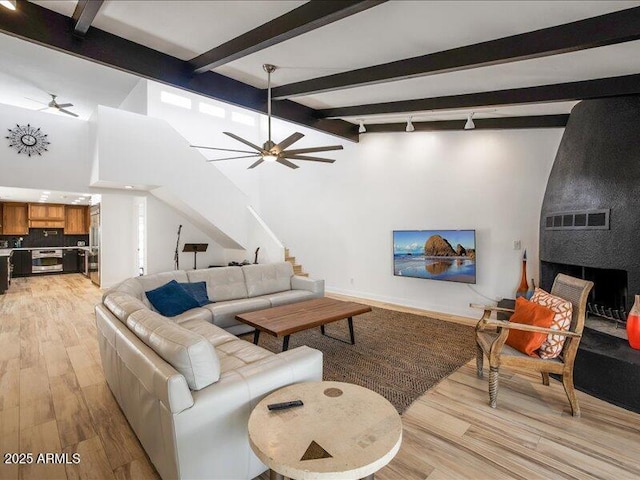 living room with ceiling fan, lofted ceiling with beams, and light hardwood / wood-style flooring