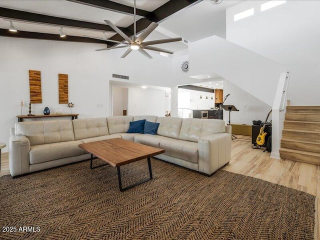 living room featuring ceiling fan, hardwood / wood-style flooring, beamed ceiling, and a high ceiling