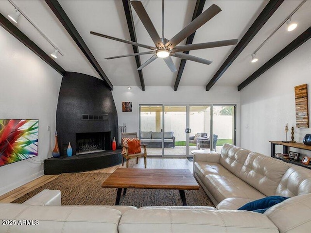 living room with rail lighting, beam ceiling, hardwood / wood-style flooring, ceiling fan, and a fireplace