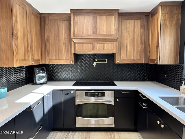 kitchen featuring oven, black electric cooktop, and decorative backsplash