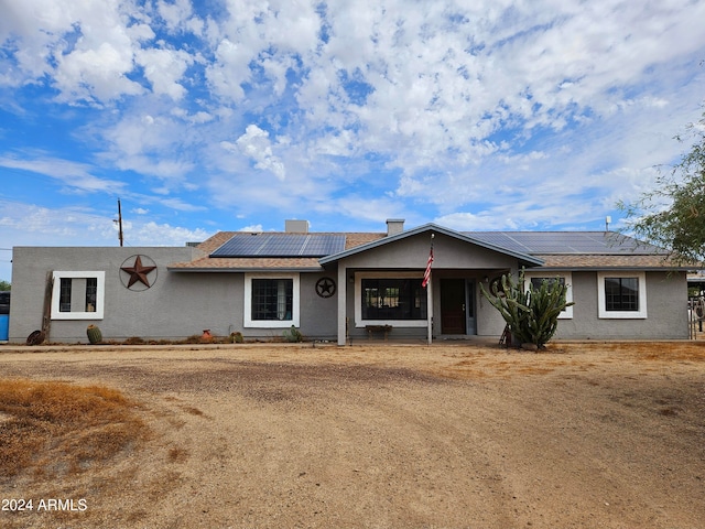 ranch-style house with solar panels and covered porch