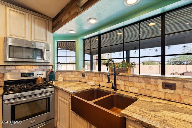 kitchen with light stone counters, appliances with stainless steel finishes, sink, and tasteful backsplash