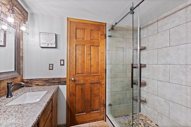 bathroom with vanity, a textured ceiling, and a shower with door