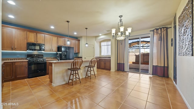 kitchen with black appliances, light tile patterned flooring, a kitchen island, and a kitchen bar