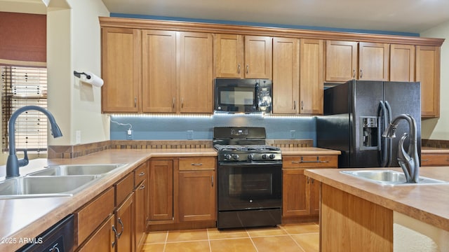 kitchen with black appliances, light countertops, a sink, and light tile patterned flooring