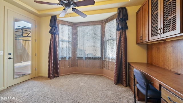 unfurnished office featuring light carpet, ceiling fan, and plenty of natural light