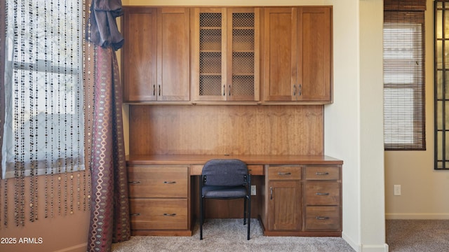 office featuring baseboards, built in desk, and light colored carpet