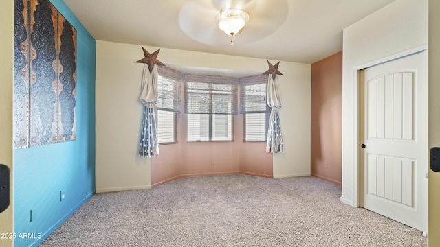 empty room with ceiling fan, baseboards, and carpet flooring